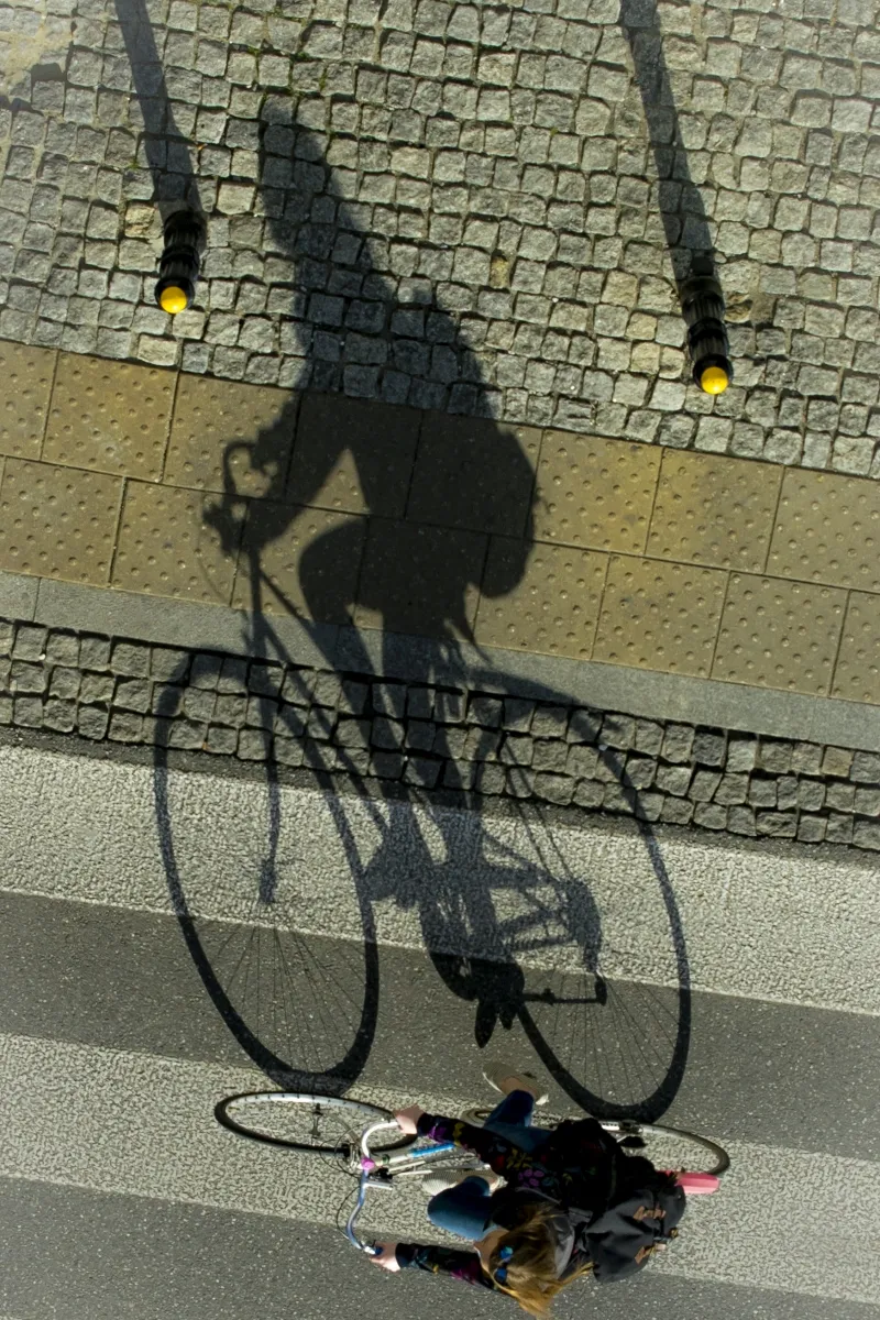 Shadow of a cyclist riding across pale paving stones